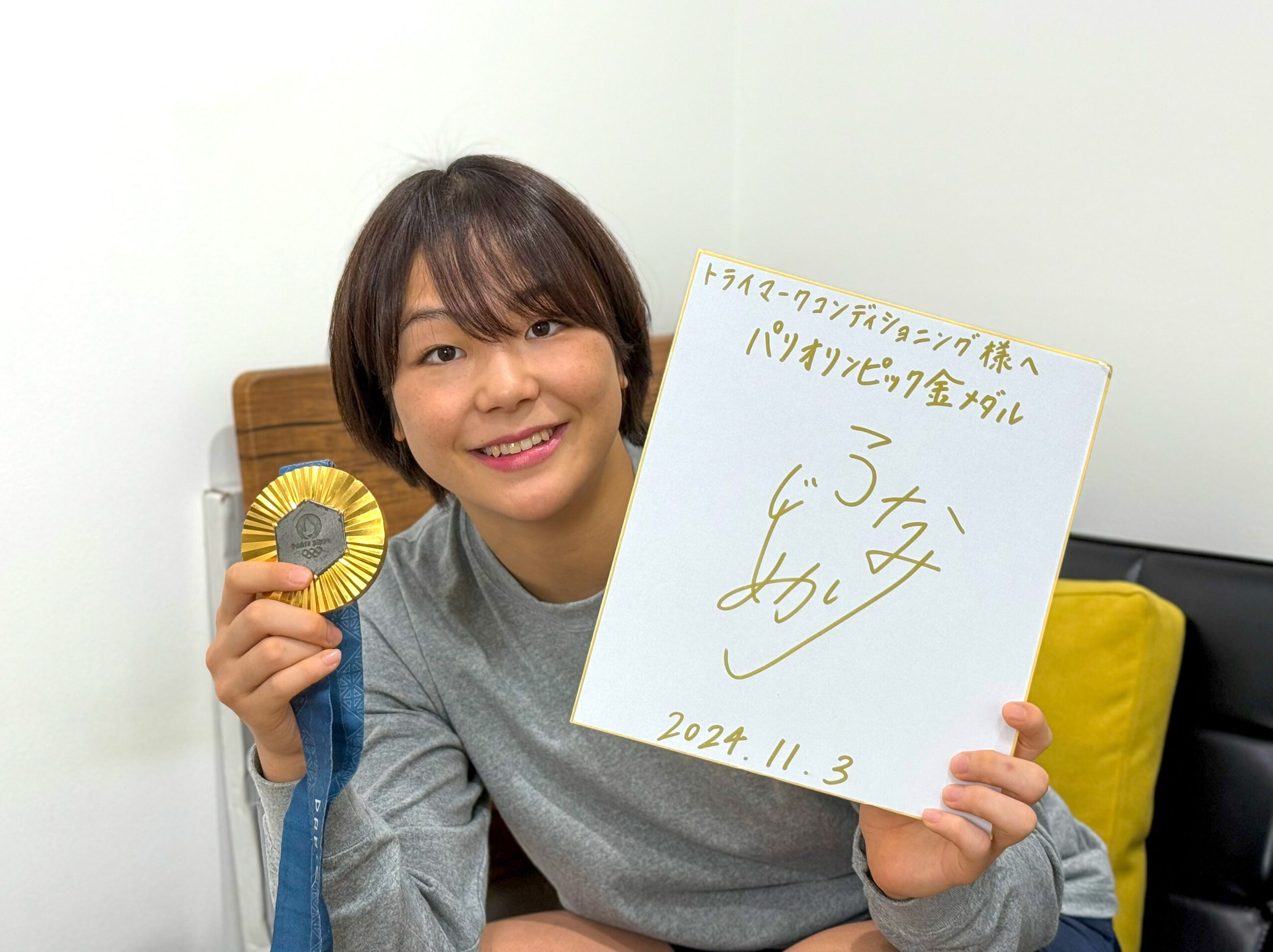 スポーツトレーナー活動 金メダルとサイン入りディスプレイを持つ藤波朱理選手の来店記録