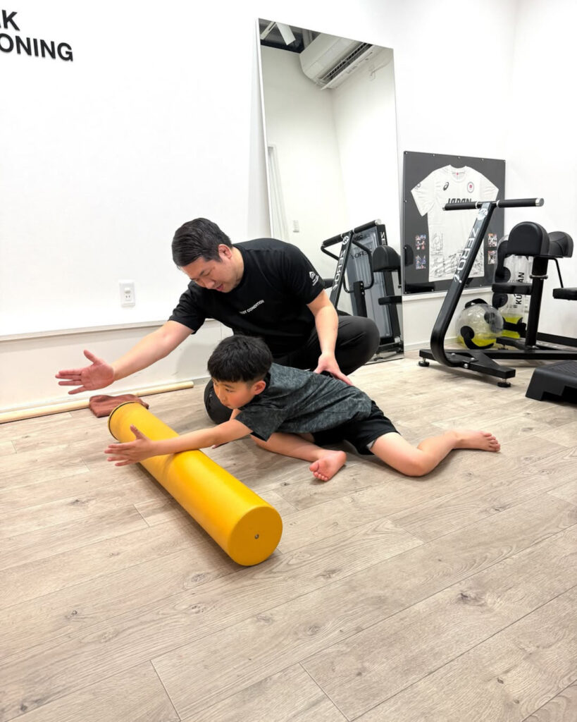 「空手に取り組む小学3年生・伊勢崇人選手にストレッチ指導を行っている様子」