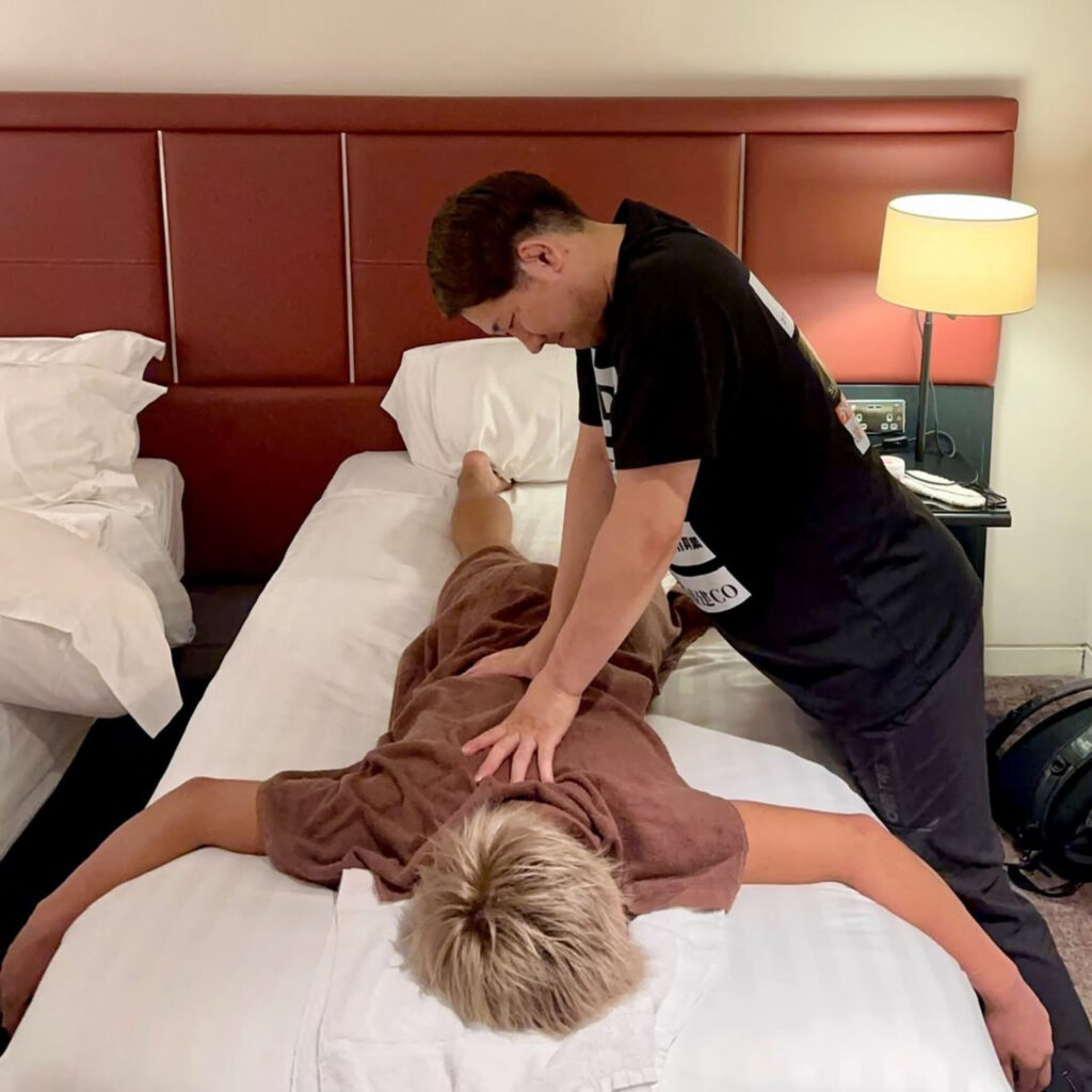 ホテルのベッドで太田忍選手の背部を手技で整えるトレーナー加藤。最終調整の疲労をリセット
