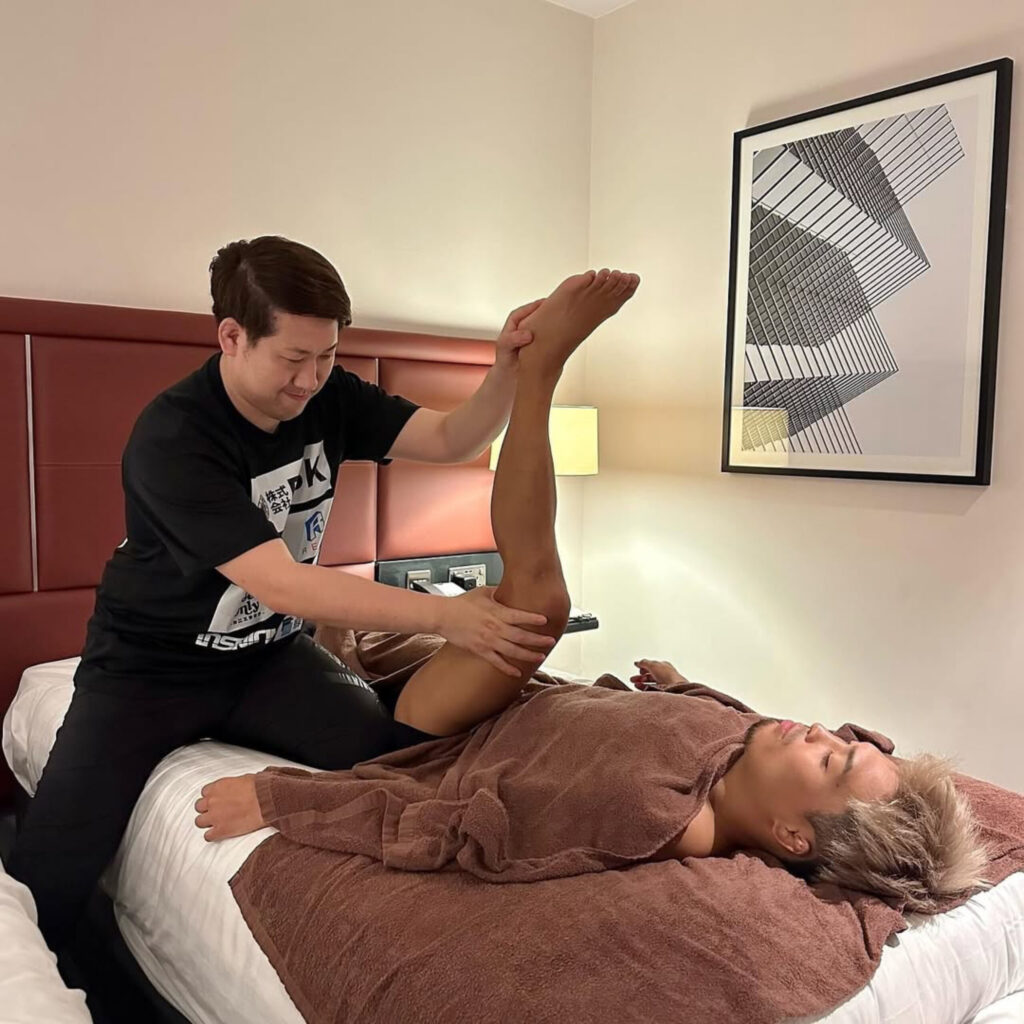 太田忍選手の脚をトレーナー加藤が丁寧にストレッチし、柔軟性と連動性を高めている様子